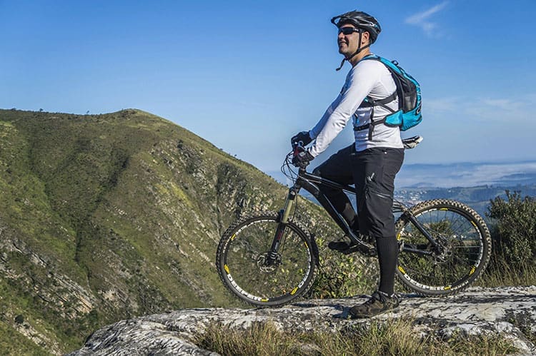 A man standing on a stone with his bicycle